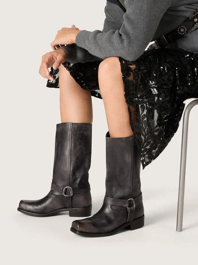 Botas moteras altas para mujer en cuero negro con correa y hebilla plateada