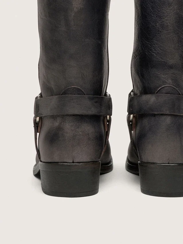Botas moteras altas para mujer en cuero negro con correa y hebilla plateada
