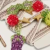 Cordones bordados a rayas en color crema y gris paloma con tres dijes de frutas con cuentas