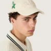 Gorra de béisbol color crema con parche «dorado» tono sobre tono y un pin de estrella verde
