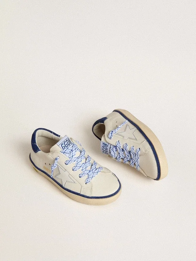 Super-Star Junior en cuero blanco con lengüeta de talón de gamuza azul